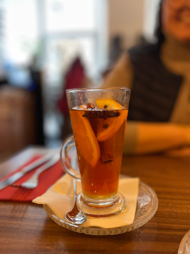 a hot tea with lemons and cinnamon sticks sitting on a table in Kluska Na Placu, Krakow Poland