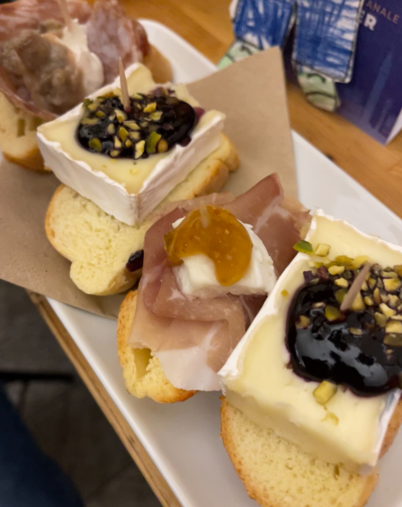 various tapas on display bread with brie and jam and one with anchovies, onions and buffala at a street food tour in venice