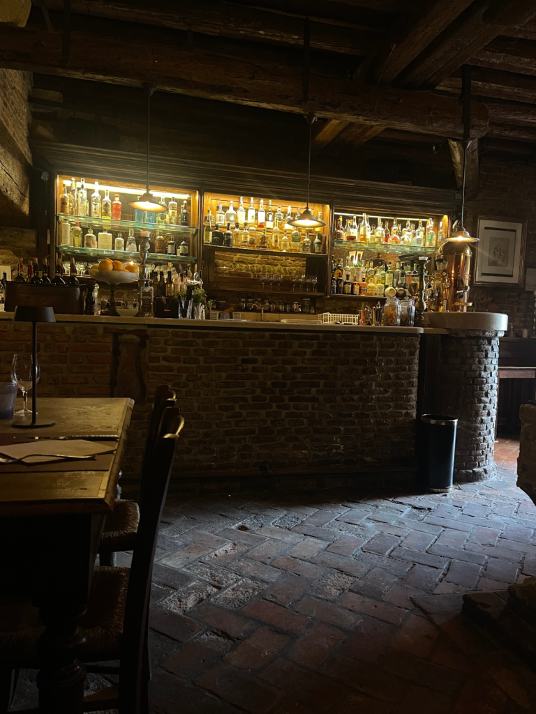 The inside of the Taverna Al Remer with a dark and cozy interior and lit up bar