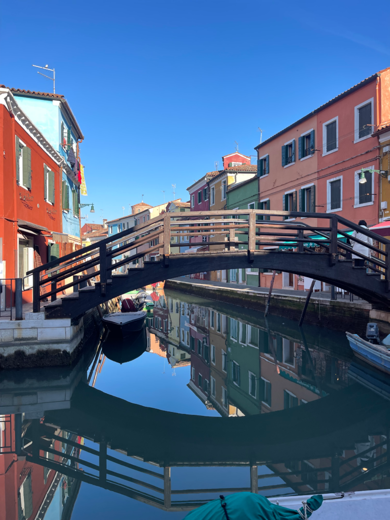 a bridge over a canale in Burano with a bright blue sky in the background
