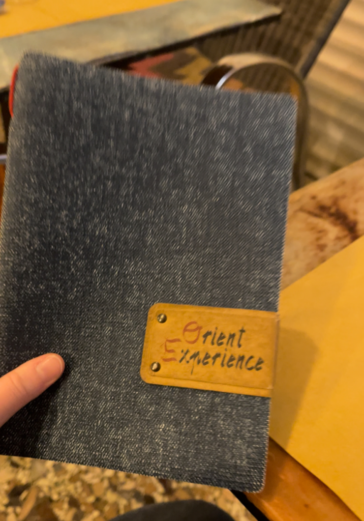 Orient Experience menu that is being held up by a hand in a restaurant