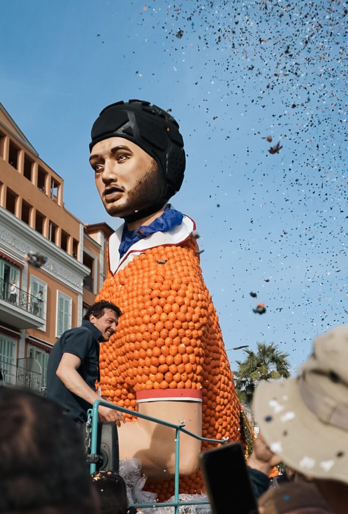 A large Fete Du Citron Float with confetti raining down on bystanders. The float is a water polo athlete