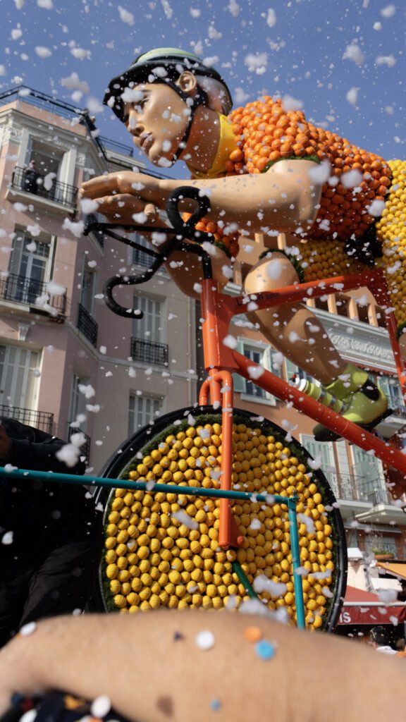 A Fete Du Citron Parade Float that is a a man on a bike made of lemons and oranges.