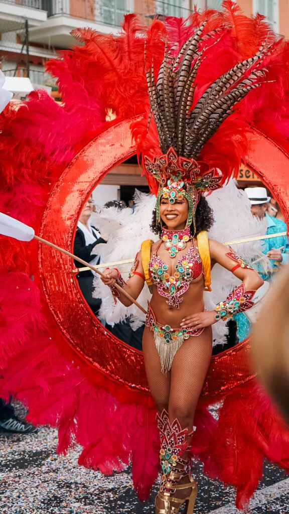 Fete Du Citron Parade. A Young lady poses in a traditional costume of brazil. Striking Red feathers and a Sparkling outfit