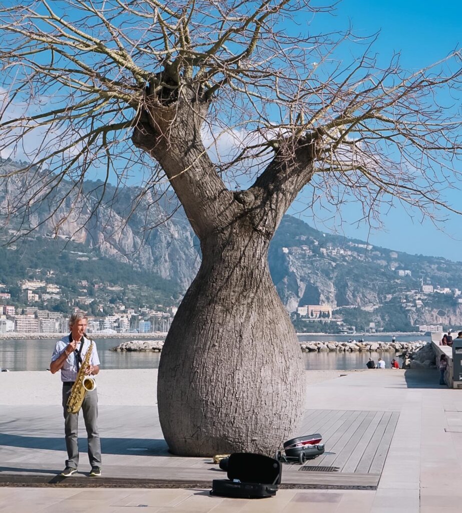 A busker plays his saxophone next to the beach in Menton.