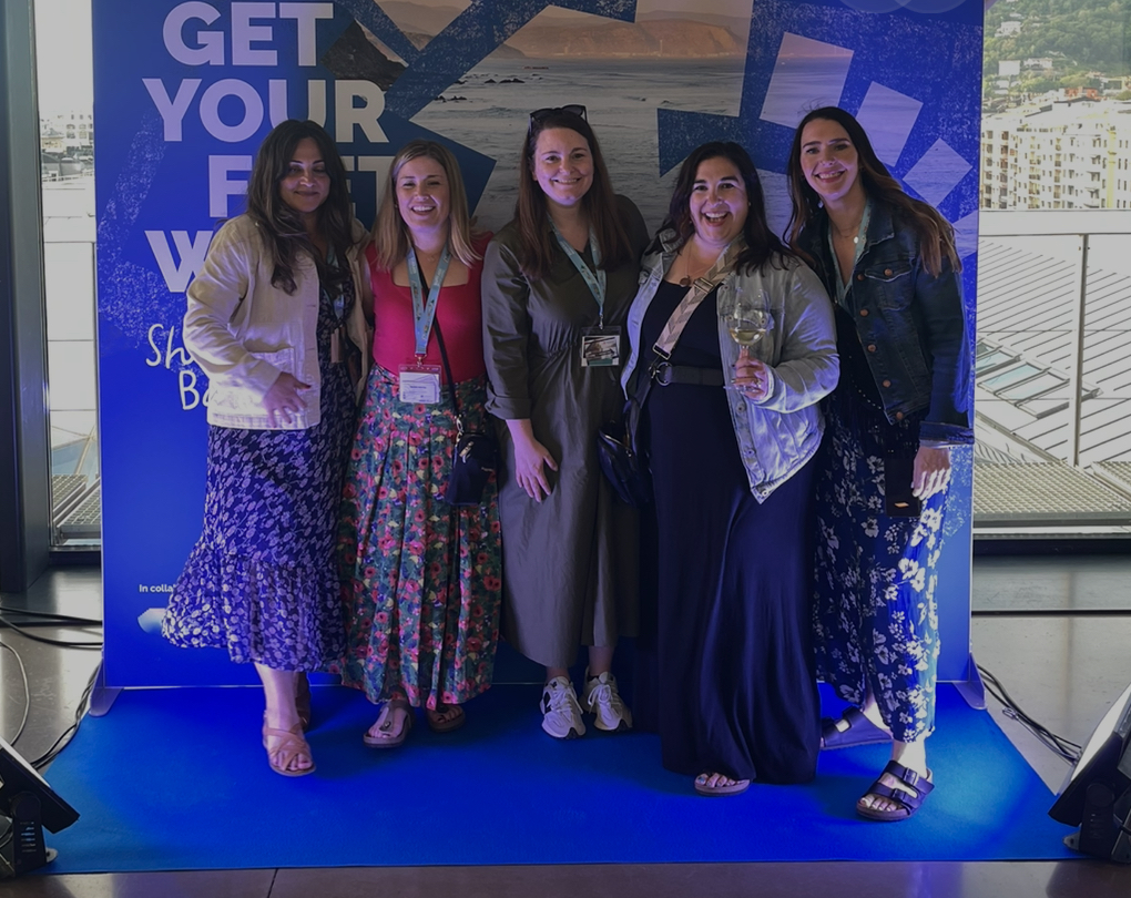a group of women standing in front of a photo backdrop that says TBEX SAN SEBASTIAN