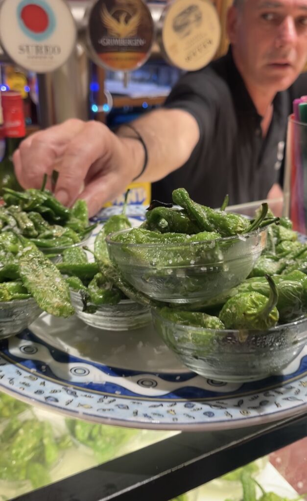 A plate of Pintxos, Gernika Peppers is being served to a patron in Bar Casa Alcalda