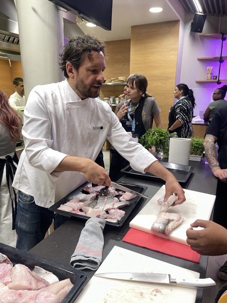 Chef at Mimo Cooking School Showing TBEX participants how to filet fish.