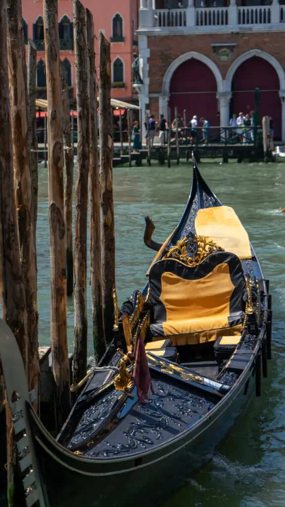 A black gondola sits empty in a venetian canal