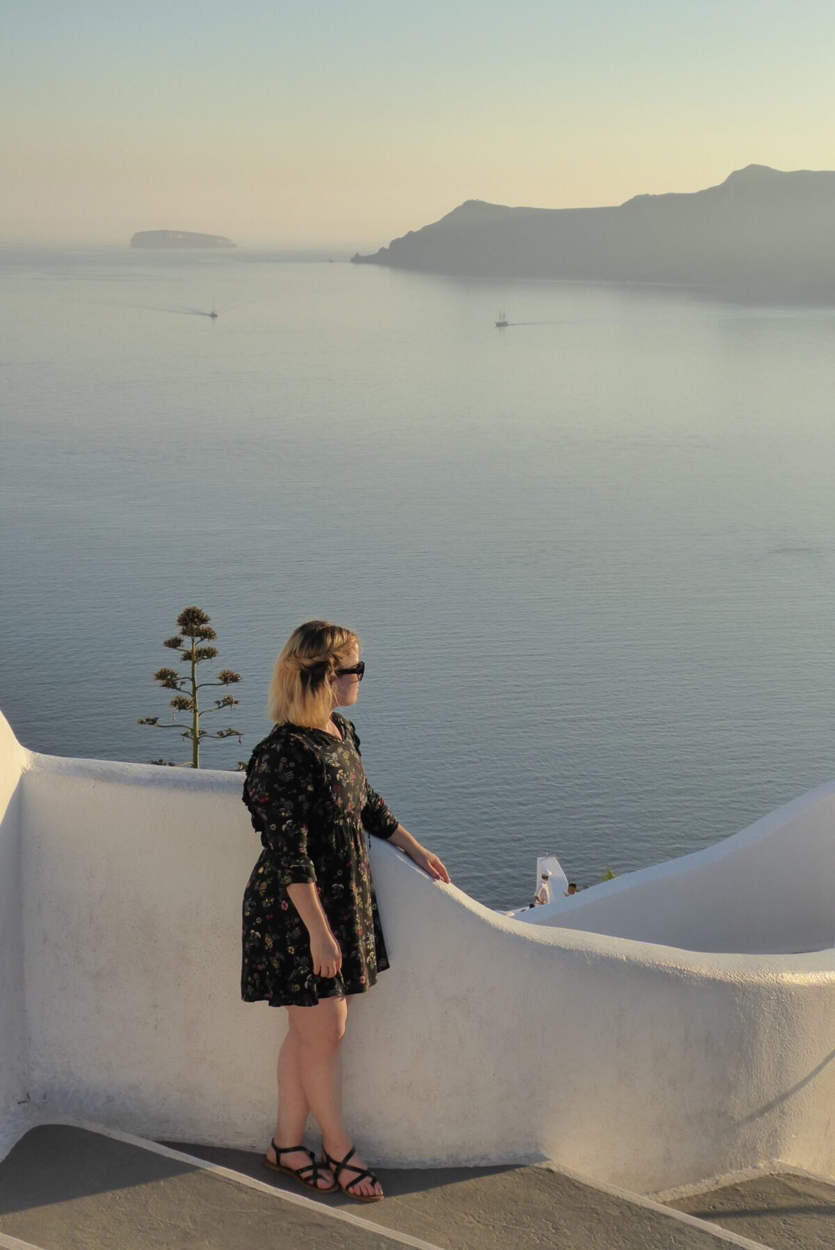 Photograph of myself standing on a walk way in Santorini with a sunset and great views after getting over culture shock