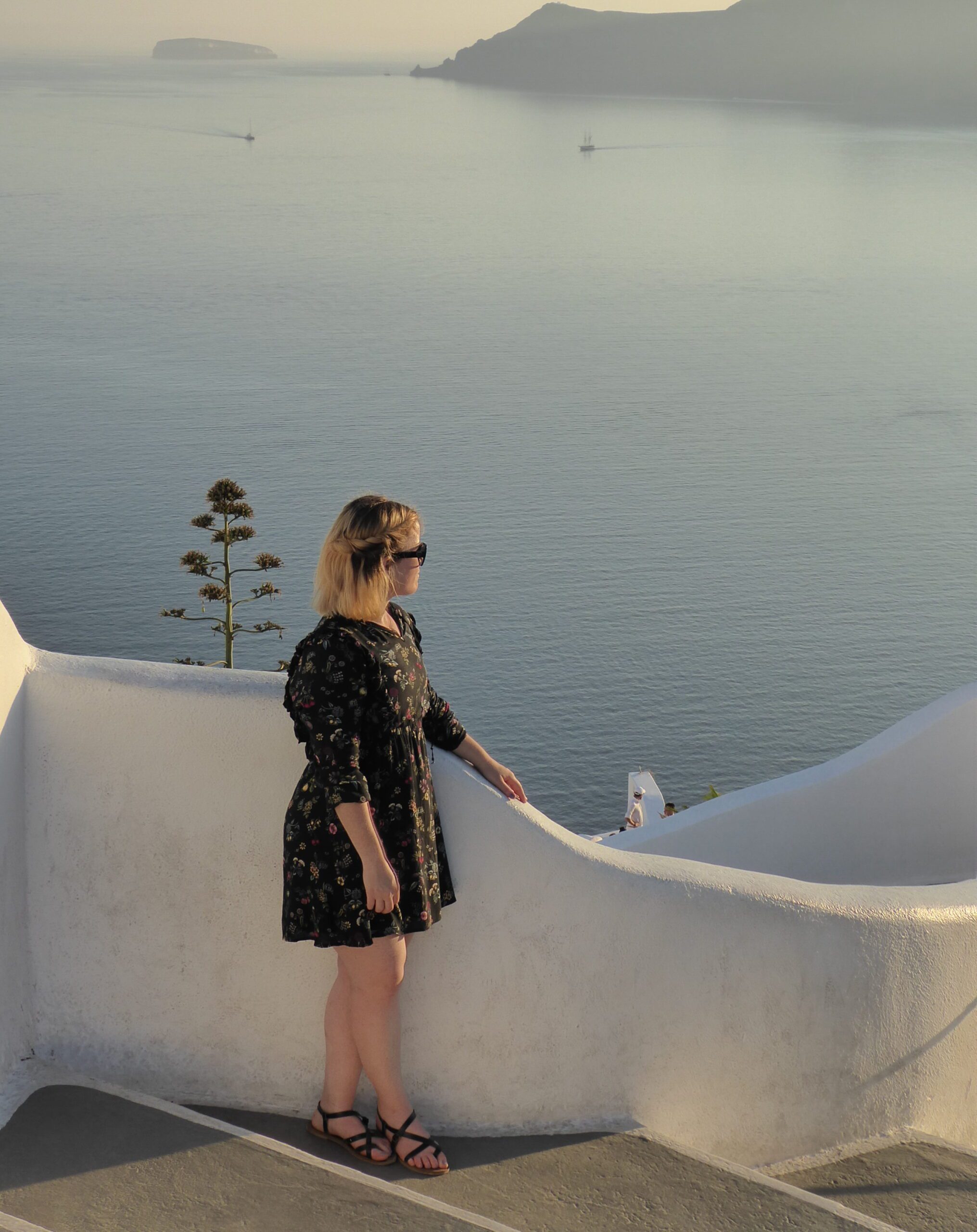 Photograph of myself standing on a walk way in Santorini with a sunset and great views after getting over culture shock