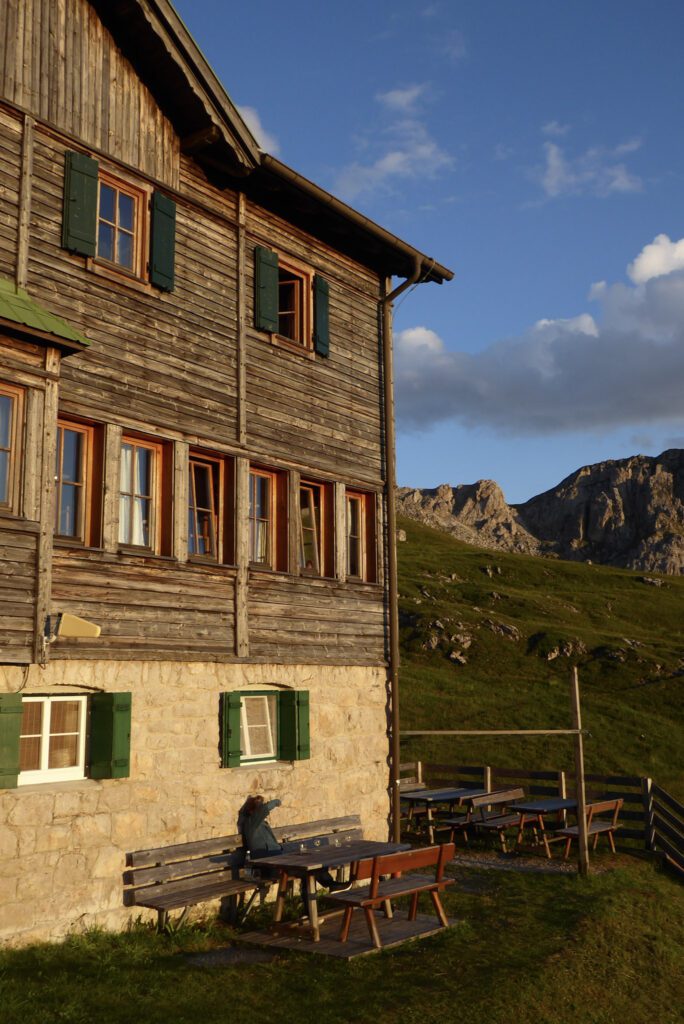 Side view of a Rifugio in the Dolomites. A person watches the sunsetting.