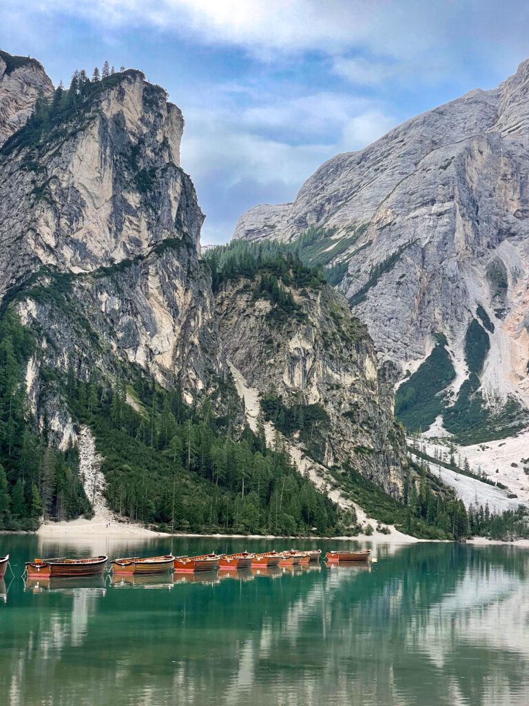 Boats lined up in lago di bries with a mountain backdrop