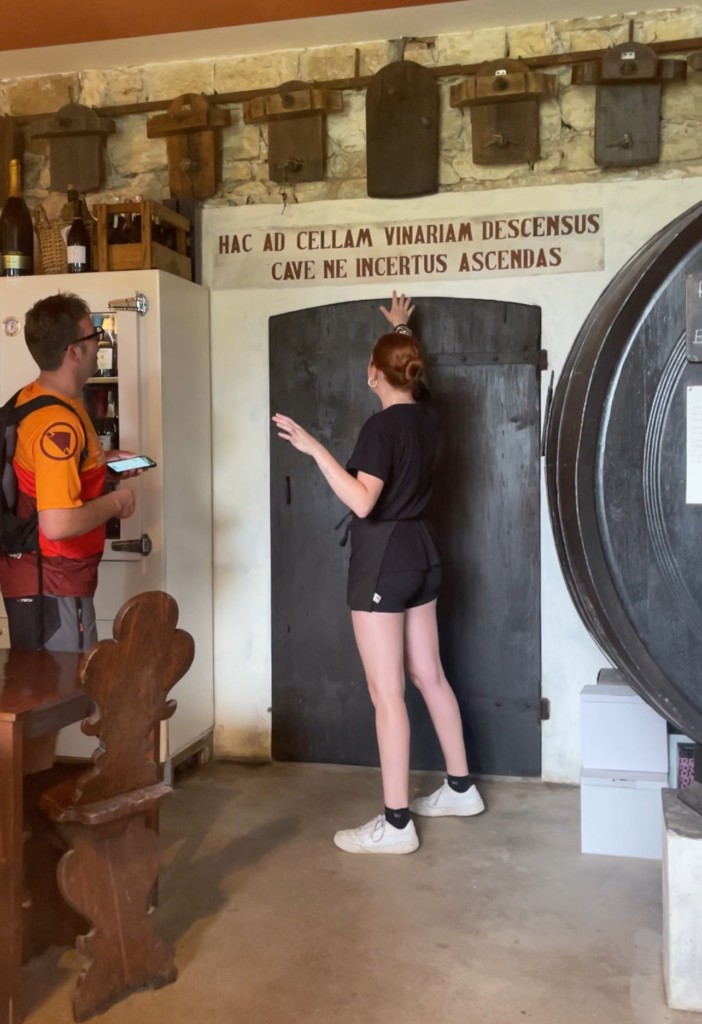 a woman standing in front a door pointing at words while a man looks on