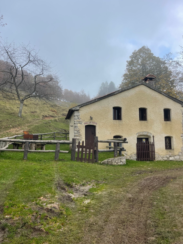 Stone mountain house surrounded by autumn foliage near Sentiero Grandi Alberi trail
