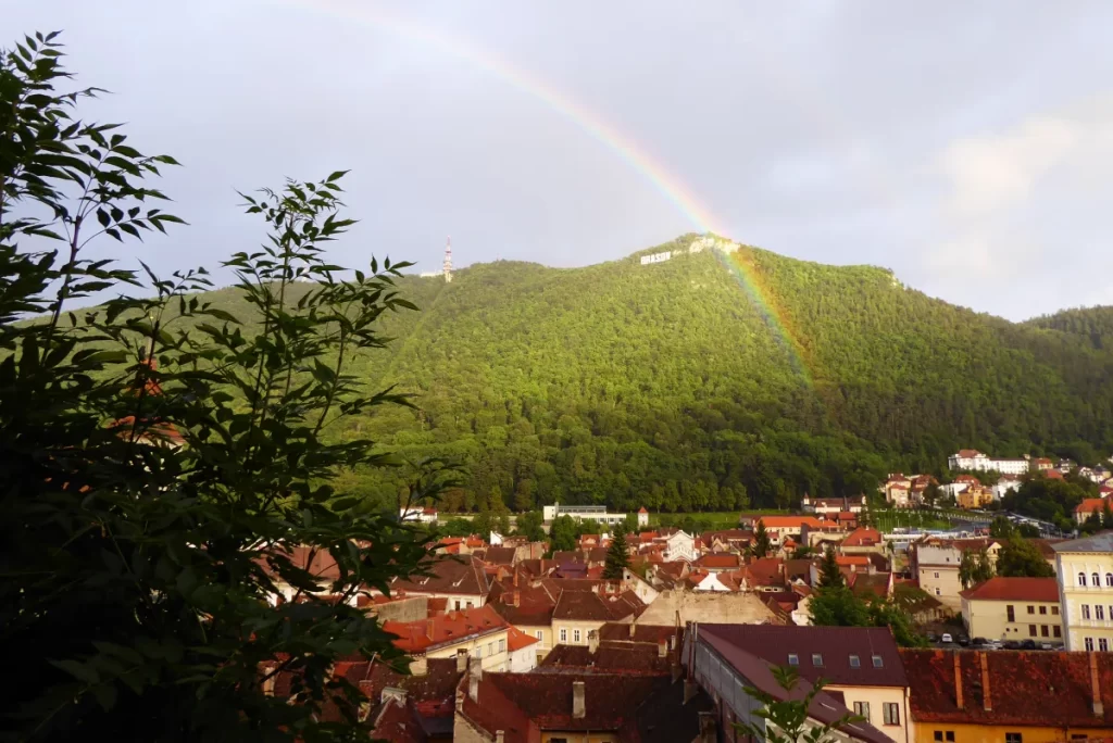 View of red rooftops and a rainbow in Brasov, Romania. Transformative travel