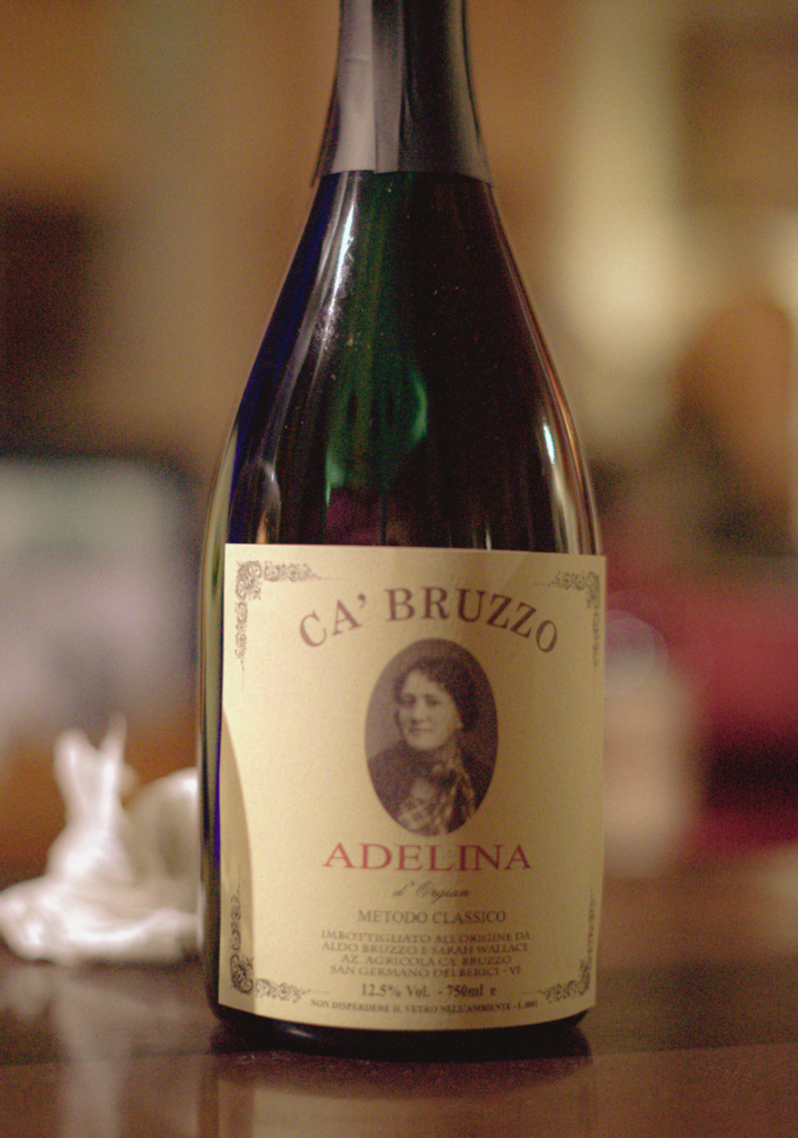 A close-up of Ca’ Bruzzo’s Adelina sparkling wine bottle, featuring a sepia portrait on the label and elegant vintage detailing.