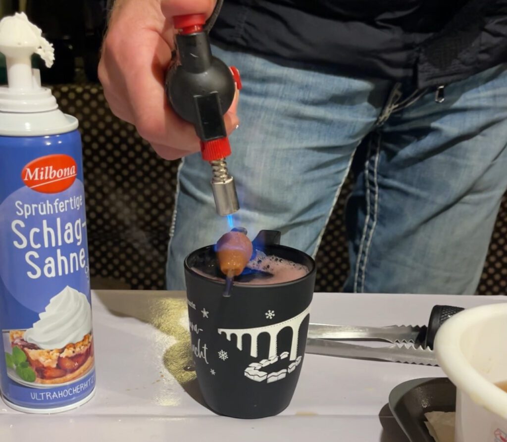 A man torching a cup of mulled wine