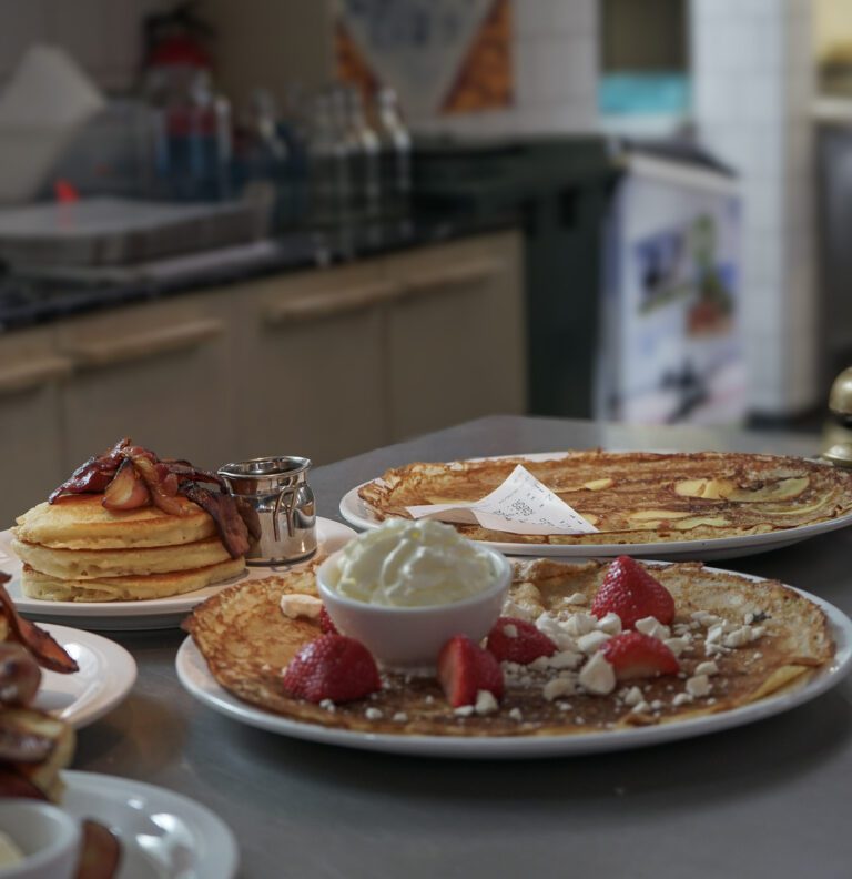 a plate of pancakes with whipped creme and strawberries at a pancake restaurant on a food tour in amsterdam