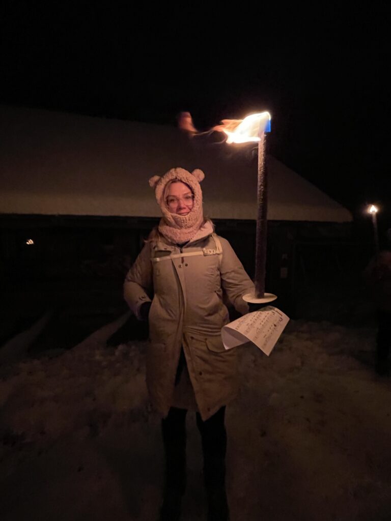 A Woman looking serious with her hat and coat holding a torch on the torchlit Fackelwanderung