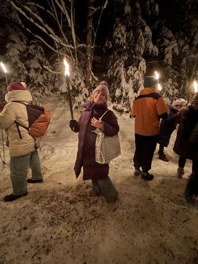 Woman with a torch walking to the Ravenna Gorge Christmas Market. This is called a Fackelwunderung