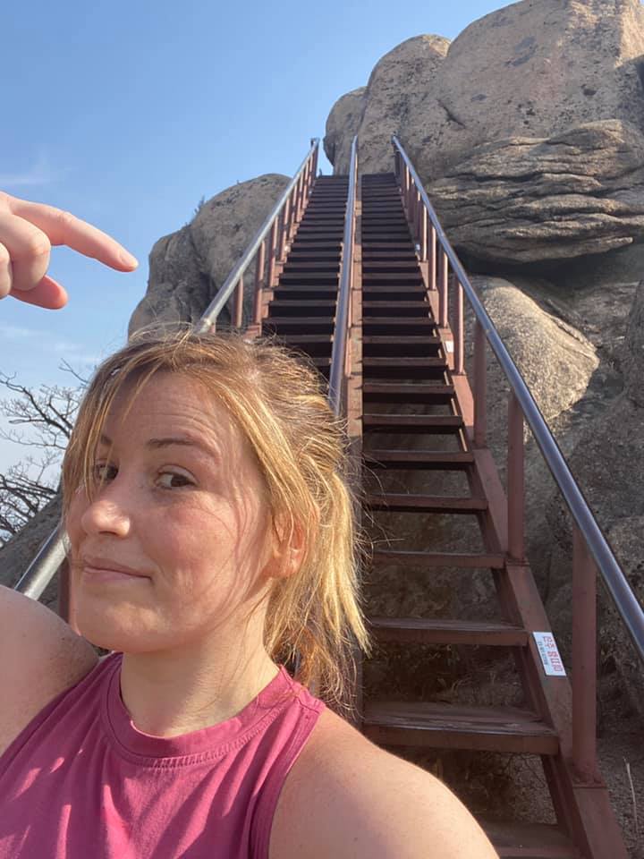 Woman with blonde hair pointing to the endless stairs getting to the top of the peak of Songnisan