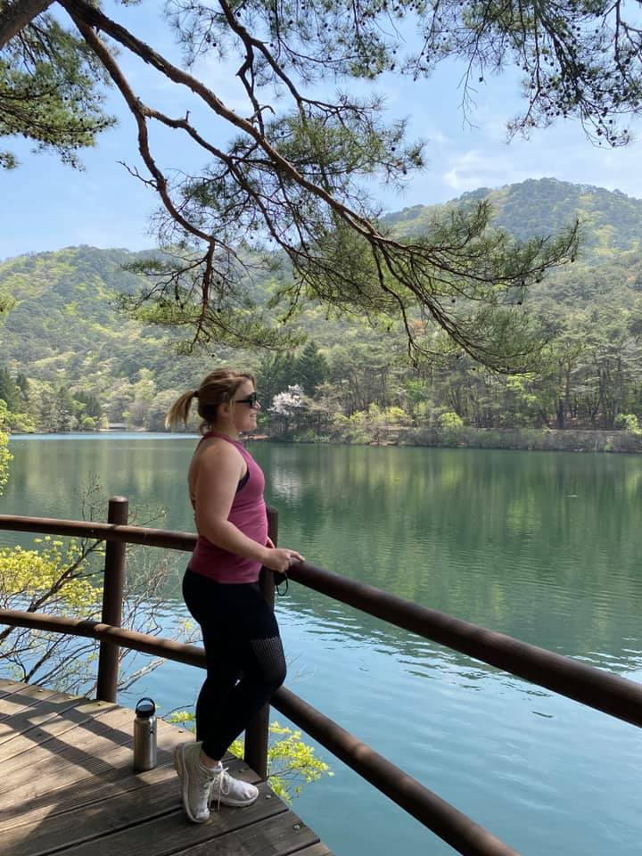 Woman with a pink tank top and black workout pants standing next to Sangpan Reservoir in Songnisan National Park