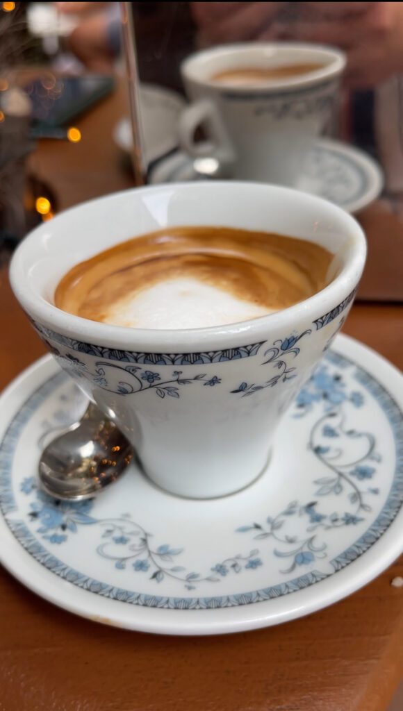 Coffee in an ornate coffee cup with a spoon on a table at Cafe Pigafetta 