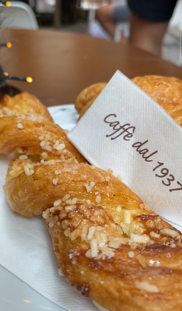 A Pastry with topped with almonds, with a napkin that says Caffe Dal 1937