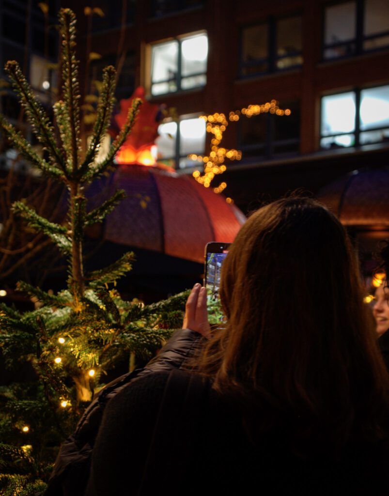 Woman holding a phone up taking a video of flames from a copper roof at the Marche De Noel in Hamburg 