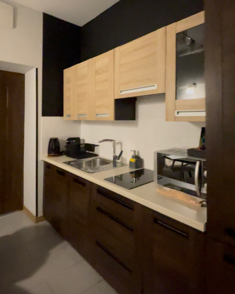 a brown cabinet kitchenette with a microwave sink and tea kettle at Wawel residence and Boutique Hotel