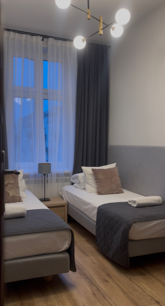 a bedroom with a window and two beds on both sides of the room with navy sheets and brown and yellow pillows