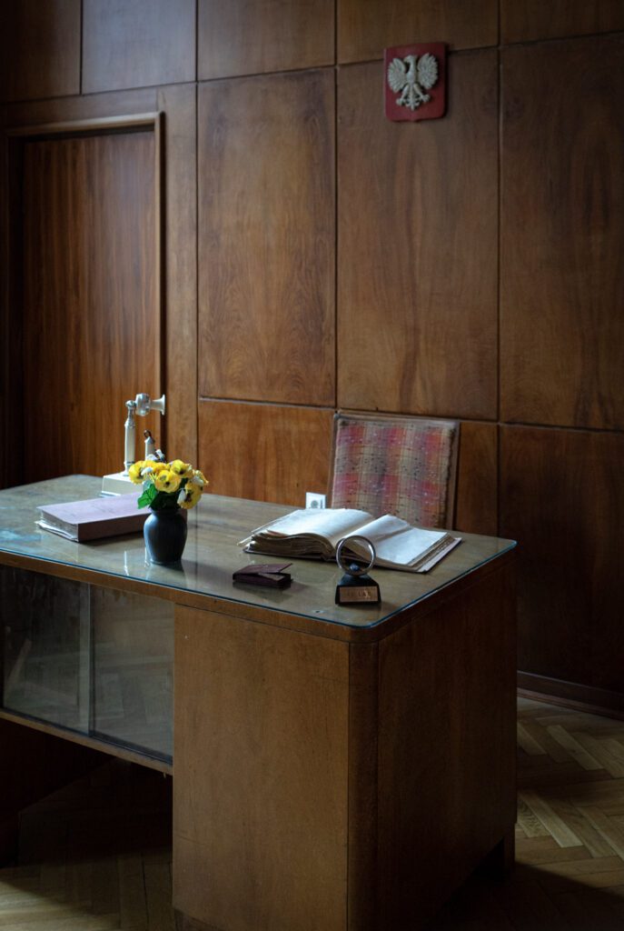 A wooden lined office with a desk and objects like a phone on it
