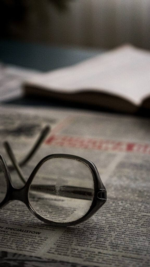 Eyeglasses lay on a table with a newspaper