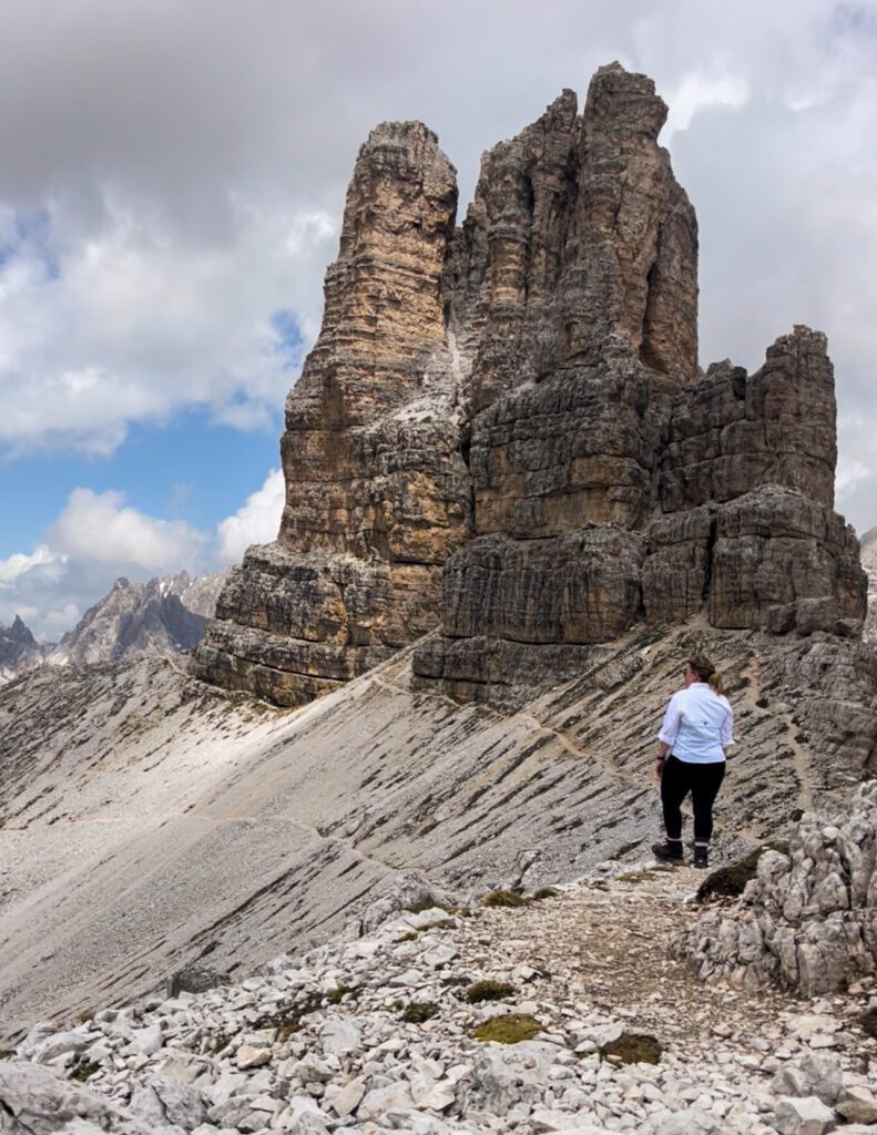 a woman in a white long sleeve shirt and black leggings is standing in front of mountain peaks