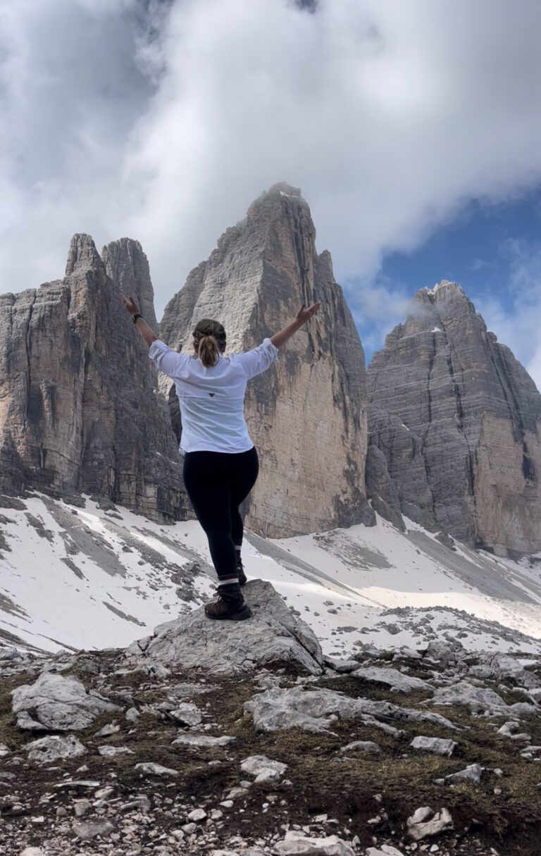 Woman with arms outstretched standing in front of Tre Cime Di Lavaredo
