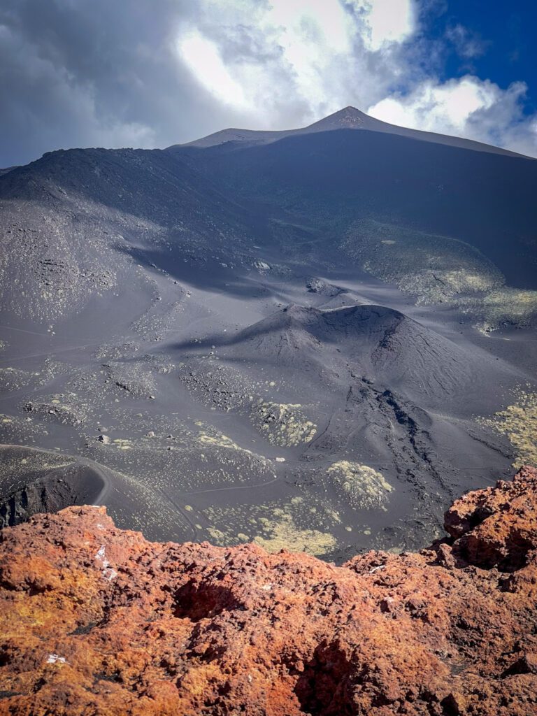Red Lava Rock stands out against black sand and blue skies