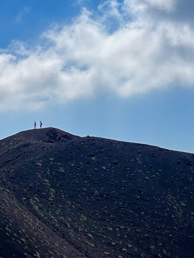 two people walking on the Mt. Etna landscape against the blue sky