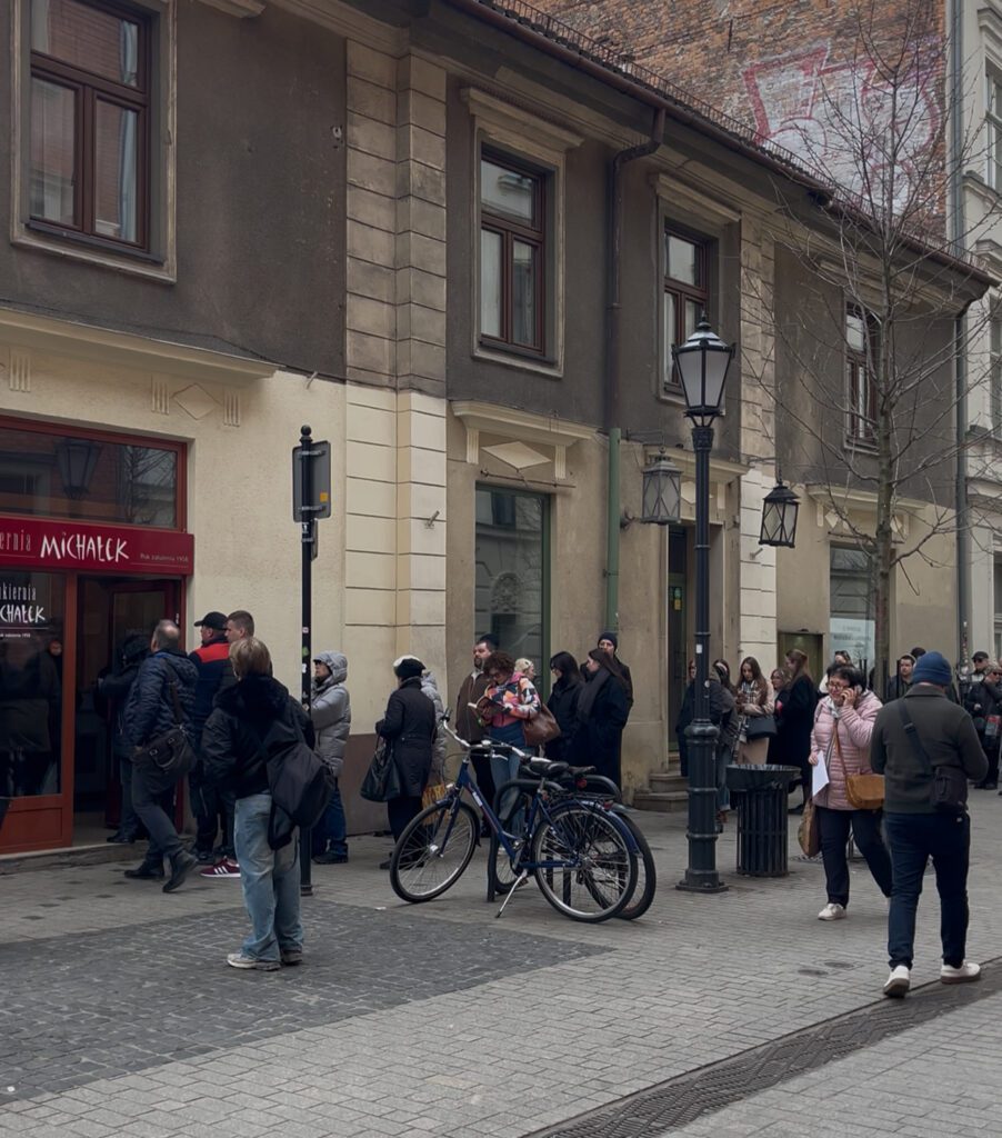 People standing in Line next to a building.