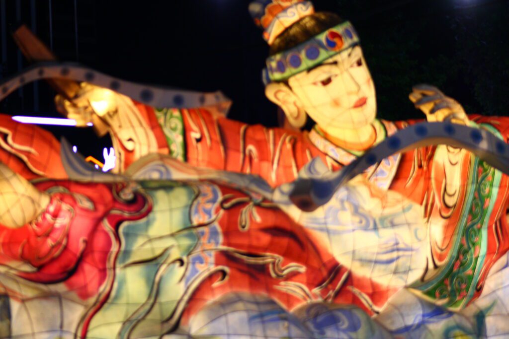A large lantern of a person is shining bright in red, yellow and green at the Lantern Festival in Seoul