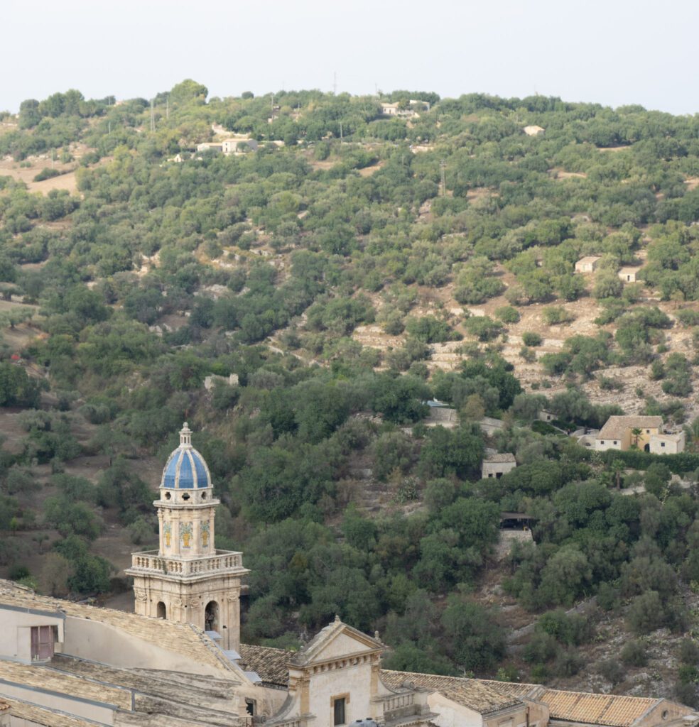 a church tower sits against the hills of Ragusa