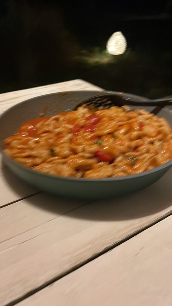 A skillet full of red pasta on a wooden table