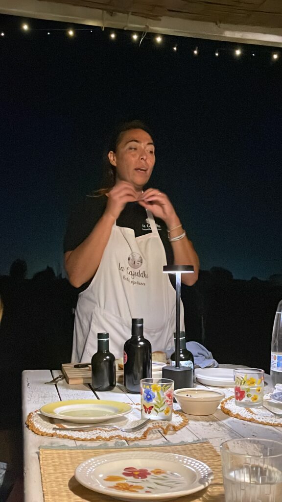 A woman with a black t-shirt and Apron showcasing olive oil