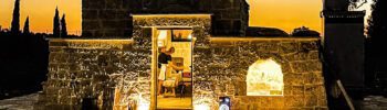 A traditional masseria in Puglia is lit up with lights against the night sky
