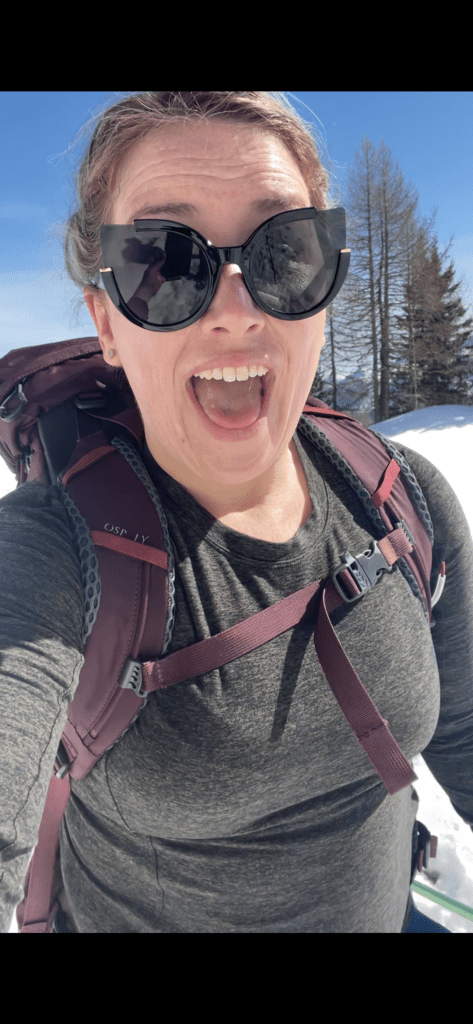 A woman smiling to the camera while snowshoeing in the dolomites