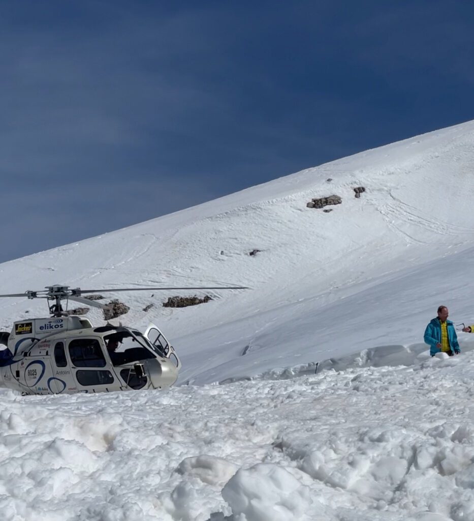 a heliocopter landing on the snow in the dolomites