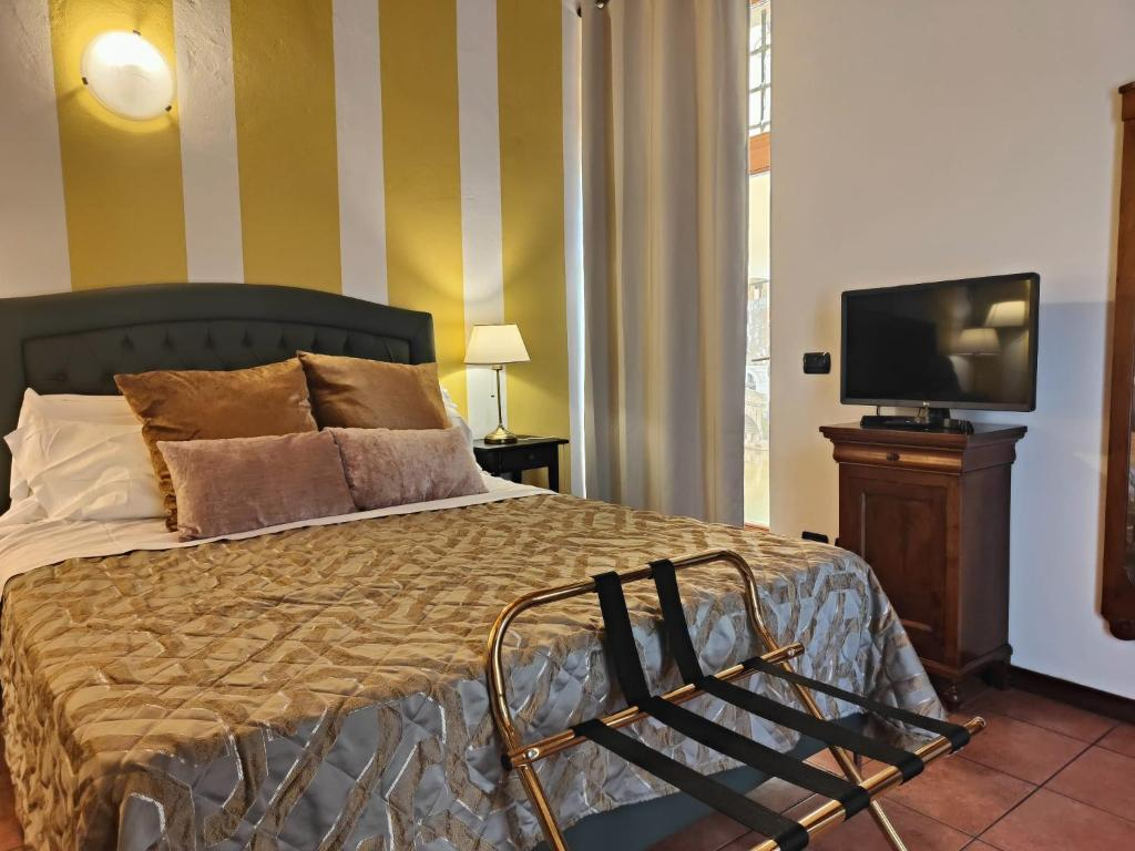 A cozy bedroom at Veronetta House in Verona featuring a tufted headboard, golden and taupe throw pillows, a patterned bedspread, and a small flat-screen TV atop a wooden cabinet.