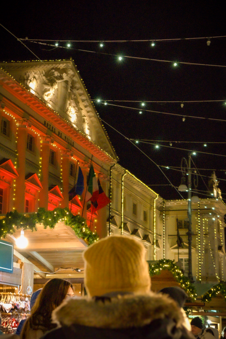 City hall in Aosta covered in colorful christmas lights in red and gold on a dark winter night