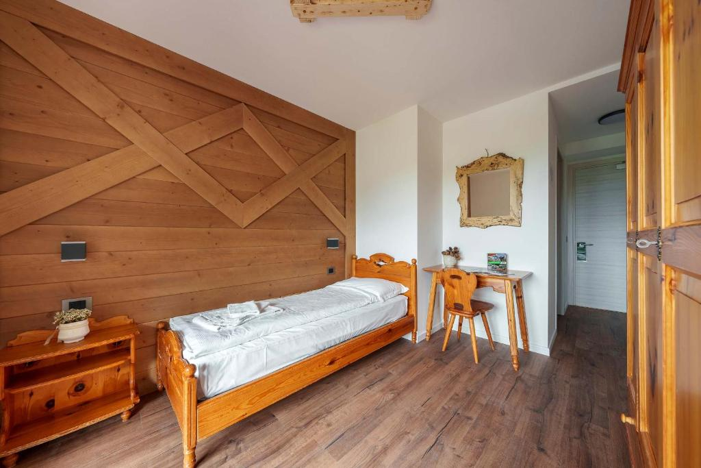 a hotel room in the dolomites with wooden accent wall and white walls with a bed and white sheets.