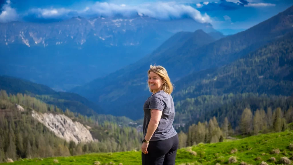 woman in blue shirt and black pants standing on a mountain side in the Dolomites